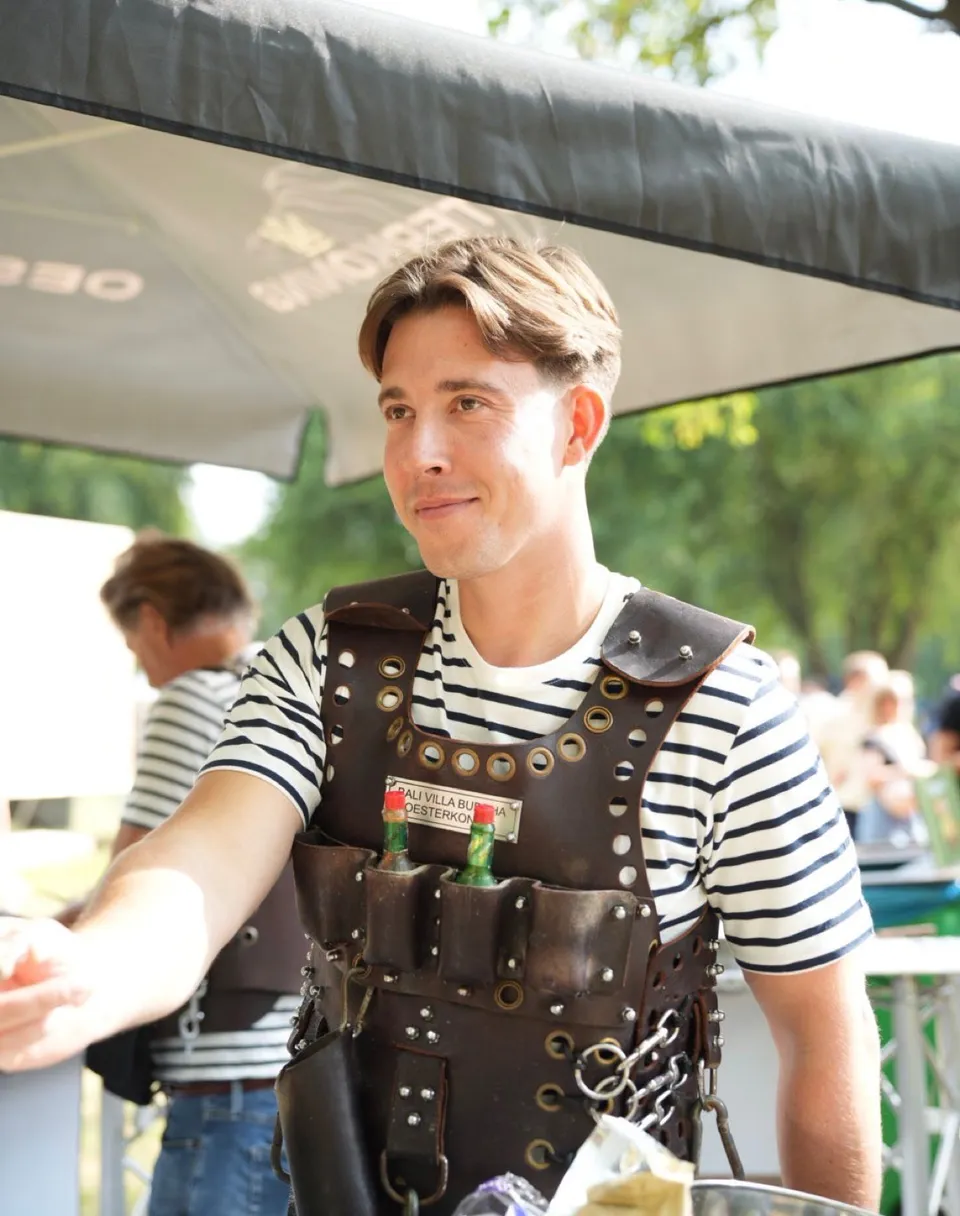 Oesterman in een leren serveeroutfit tussen de gasten.